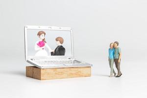 pessoas em miniatura noiva e noivo casamento virtual na tela do computador foto