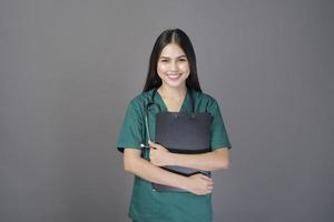 jovem médico mulher bonita feliz vestindo um avental verde está segurando documentos foto