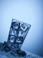 copo de água com cubos de gelo em um fundo azul claro foto