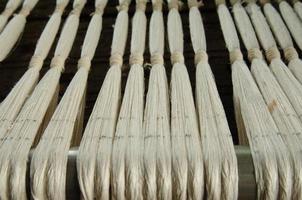 fio de tecelagem de seda sutil e closeup de fios. fibra de algodão branco foto