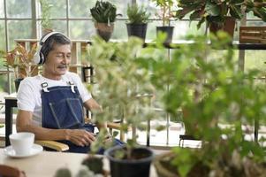 feliz aposentado asiático sênior ouvindo música e desfrutando de atividades de lazer no jardim em casa. foto