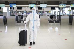 um homem asiático está vestindo traje de EPI no aeroporto internacional, viagens de segurança, proteção covid-19, conceito de distanciamento social foto