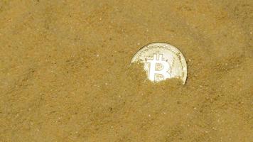 uma moeda criptográfica bitcoin na areia dourada brilhante. encontrar e minerar criptomoedas foto