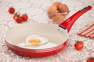 panela com ovo frito e tomate em uma toalha de mesa branca foto