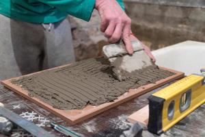 trabalhador aplica adesivo de cimento nas telhas. trabalhos de acabamento, foco desfocado. a tecnologia de colocação de azulejos foto
