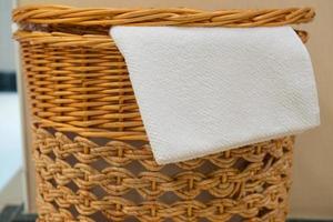 toalha branca em uma cesta de vime no banheiro do hotel foto