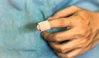 close-up de uma bandagem no dedo indicador de um homem contra um fundo azul. recuperação de emergência de primeiros socorros de cuidados de saúde. foto