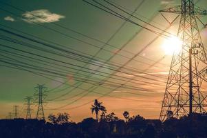 poste de torre de estação de planta de linha de energia elétrica no campo no fundo do pôr do sol. poder de energia abstrato. foto