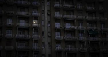 uma janela iluminada por luz elétrica destaca-se na fachada de um edifício na ligúria ocidental foto