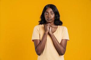 mulher africana calma em pé com os olhos fechados e esperando por algo foto