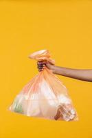 mãos femininas segurando saco de lixo plástico laranja foto
