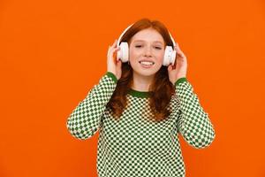 mulher ruiva feliz na camisola xadrez ouvindo música com fones de ouvido foto