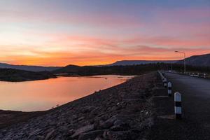 crepúsculo céu rio pôr do sol roxo e laranja cor paisagem lago noite nuvens e montanhas foto