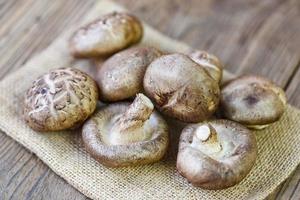 cogumelos frescos no saco e fundo de mesa de madeira - cogumelos shiitake