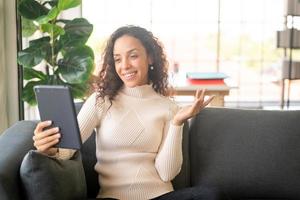 mulher latina videoconferência em tablet com sentimento de felicidade foto