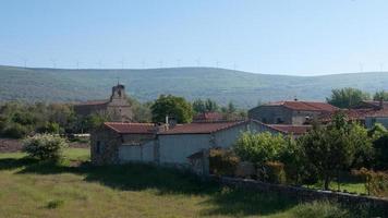 bela vila espanhola com casas de pedra. turbinas eólicas nas colinas atrás foto