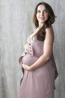 menina grávida em fundo cinza. foto