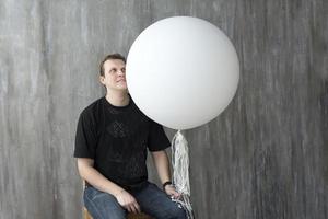um homem segurando uma bola inflável em um fundo cinza. foto