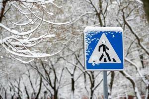 sinal de estrada coberto de neve na rua da cidade foto