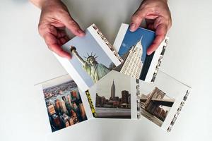mãos de mulher segurando impressões de fotos da cidade de nova york, isoladas no fundo branco. viajando no conceito dos eua.