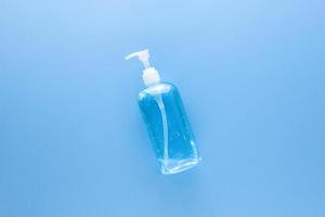 álcool gel desinfetante para as mãos em garrafa de bomba transparente para proteger de germes e coronavírus em fundo médico azul claro foto