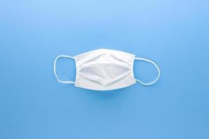 nova máscara facial médica branca limpa isolada na vista superior de fundo de papel azul claro foto