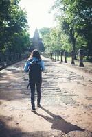 vista traseira do turista jovem atraente com mochila vindo para tirar foto no antigo templo phanom degrau na tailândia.