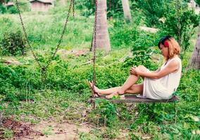 mulher jovem hippie, triste, cabelos compridos sentado abraçando as pernas. foto