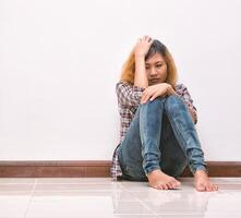 mulher jovem hippie, triste, cabelos compridos sentado abraçando as pernas. foto