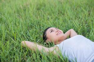 bela jovem deitada em prados de grama verde. foto