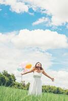 mulher bonita jovem feliz com balões no campo de grama desfrutar com ar fresco. foto