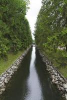 um pequeno canal de água com árvores coníferas e uma ponte. foto