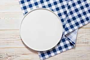 prato vazio na toalha de mesa sobre a vista superior de fundo de madeira foto