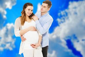 retrato de jovem casal aguardando o garoto isolado em fundo azul, jovem casal atraente mãe grávida e pai feliz, lindo casal jovem esperando bebê foto