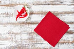 pimenta vermelha quente e guardanapo de papel na velha mesa de madeira, conceito de férias foto