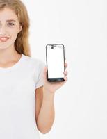 sorria linda garota, mulher de camiseta segura celular de tela em branco isolado no fundo branco. braço segurando smartphone, copie o espaço foto