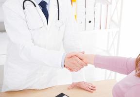 mão masculina do médico aperta o braço feminino de seu paciente na clínica, consultório médico. conceito de saúde, seguro saúde foto