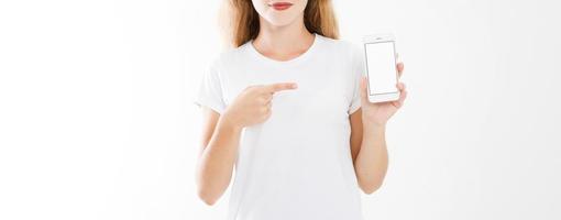 jovem, mulher em t-shirt que aponta o dedo para celular de tela em branco isolado no fundo branco. mão segurando o smartphone. copie o espaço foto