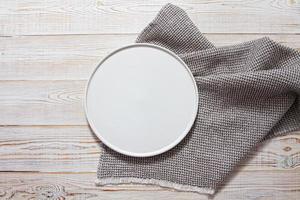 prato branco vazio com guardanapo na mesa de madeira branca
