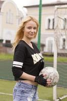 linda loira com uma bola no gol de futebol. foto