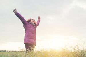 jovem espalhando as mãos e alegria com a natureza durante o inverno ao fundo do sol. foto