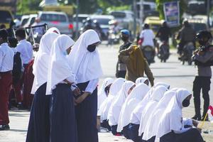 sorong, papua ocidental, indonésia, 4 de outubro de 2021. visita de estado do presidente da indonésia, joko widodo. crianças em idade escolar e professores saudaram a chegada do presidente da beira da estrada.