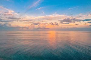 vista panorâmica aérea do pôr do sol sobre o oceano. céu colorido, nuvens e água. bela cena serena, relaxante horizonte do oceano foto