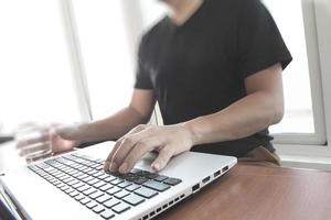 close-up da mão de homem de negócios trabalhando no computador portátil na mesa de madeira como conceito foto