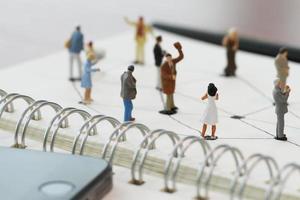 close-up de pessoas em miniatura com diagrama de rede social no notebook aberto na mesa de madeira como conceito de mídia social foto