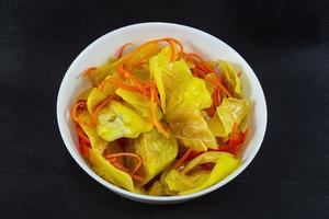 repolho em conserva com curry e cenoura em um prato em uma vista superior de fundo preto foto