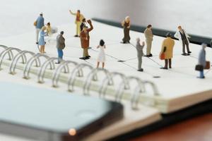 close-up de pessoas em miniatura com diagrama de rede social no notebook aberto na mesa de madeira como conceito de mídia social foto