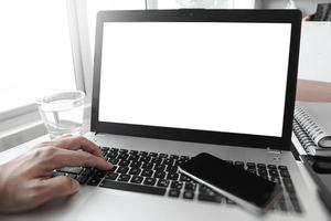 close-up da mão do homem de negócios, trabalhando no computador portátil de tela em branco na mesa de madeira como conceito foto