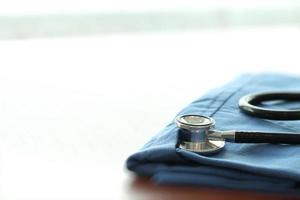 estetoscópio com casaco de médico azul na mesa de madeira com dof raso uniformemente combinado e fundo foto