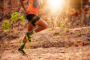 um homem corredor de trilha. e pés de atleta usando sapatos esportivos para trilha nas montanhas, foco suave e embaçado foto